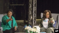 Oprah Winfrey y la candidata a la gobernación de Georgia, Stacey Abrams, saludan a una multitud reunida para una conversación en el ayuntamiento en el Teatro Jennie T. Anderson.
