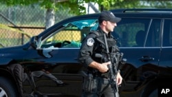 A Capitol Hill Police officer walks past an automobile with the driver's window damaged at the scene of a shooting in Alexandria, Va., Wednesday, June 14, 2017