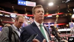FILE - Then-Trump Campaign Chairman Paul Manafort talks to reporters on the floor of the Republican National Convention, in Cleveland, Ohio, July 17, 2016. His associate, Richard Gates, is seen in the background (left).
