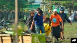 Varias personas cargan el cuerpo de una víctima del tsunami en Palu, Sulawesi central, Indonesia, el domingo 30 de septiembre del 2018.