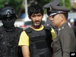 FILE - Police officers escort a key suspect in the Bangkok bombing, yellow shirt, identified by Thai police as Yusufu Mierili, also as Yusufu Mieraili, traveling on a Chinese passport, but his nationality remains unconfirmed, Sept. 9, 2015.