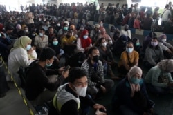 Orang-orang yang memakai masker pelindung mengantri untuk vaksin COVID-19 di Bandara Internasional Juanda, saat kasus melonjak di Sidoarjo, Jawa Timur, 22 Juli 2021. (Foto: Antara/Umarul Faruq via REUTERS)