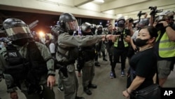 Police in riot gear ask a woman to take off her mask outside a train station in Hong Kong, Nov. 3, 2019. 
