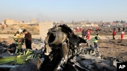 FILE - Debris is seen from an Ukrainian passnger plane which crashed as authorities work at the scene in Shahedshahr, southwest of the capital Tehran, Iran, Jan. 8, 2020. 