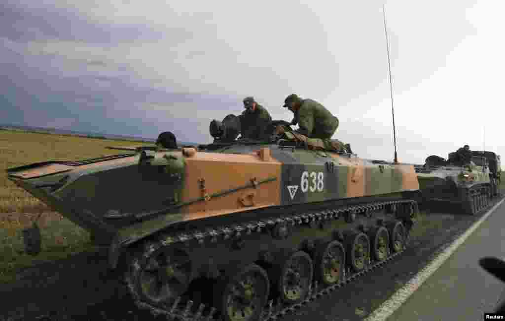 Russian servicemen sit on military vehicles by the roadside, outside Kamensk-Shakhtinsky, near the border with Ukraine, Rostov Region, Aug. 18, 2014. 