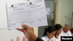 A member of the National Election Committee (NEC) and NEC's spokesman Dim Sovannarom shows a registration of political parties list to the media in Phnom Penh, Cambodia, April 30, 2018. 