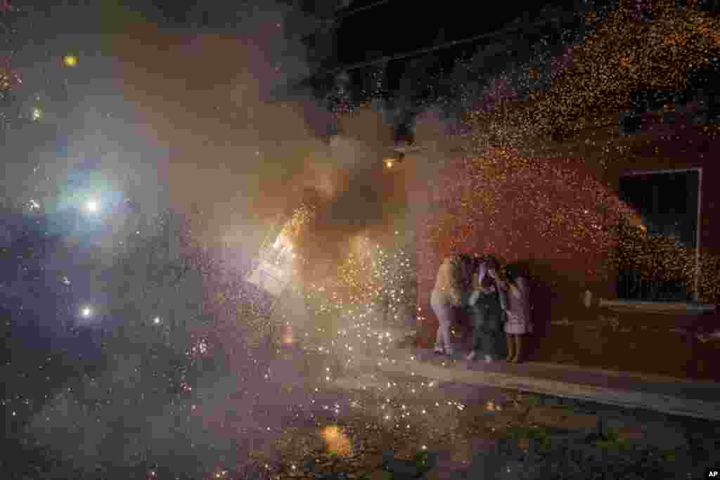People cover themselves in front of a man wearing a "torito," a bull-shaped harness equipped with fireworks, during a Christmas celebration in Antigua, Guatemala, Dec. 25, 2021.