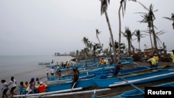 FILE - Homeless typhoon victims gather near their new fishing boats given by a religious organization along a coastal village devastated by super Typhoon Haiyan in Tacloban city, central Philippines.