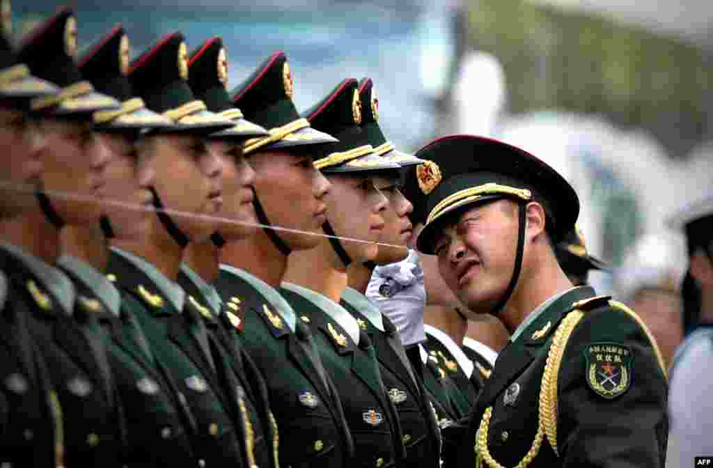 Regu penjaga kehormatan China mempersiapkan diri untuk menyambut kedatangan Presiden Myanmar ( yang juga dikenal sebagai Burma) U Thein Sein dan Presiden China Xi Jinping dalam upacara kehormatan di luar balai kota rakyat di Beijing. Sebuah benang direntangkan untuk memastikan mereka berdiri dalam garis lurus. 