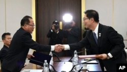 韩国统一部次长千海成(右)和朝鲜代表团团长田钟秀在韩国非军事区板门店举行会谈时握手.(2018年1月17日 韩国统一部提供)