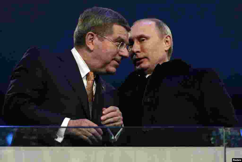 International Olympic Committee President Thomas Bach of Germany talks to Russian President Vladimir Putin during the opening ceremony of the 2014 Sochi Winter Olympics, Feb. 7, 2014.