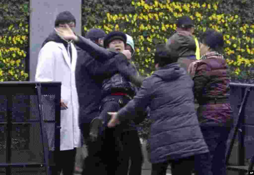 A New Year's Eve stampede victim reacts as she is taken away by officials at the site of a memorial ceremony for people who were killed in the tragic accident in Shanghai, China, Jan. 6, 2015.