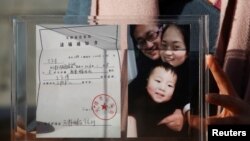 資料照：中國維權律師王全璋的妻子李文足手舉全家福照片和天津警方的逮捕通知書。 （2018年12月17日）