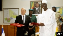 FILE - Malian Defense Minister Bah N'Daw, right, and his French counterpart Jean-Yves Le Drian meet in Bamako, July 16, 2014. Bah N'Daw was appointed president of Mali during the transition period.
