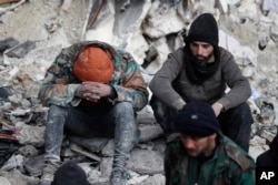 Orang-orang duduk di reruntuhan bangunan pasca gempa, di Aleppo, Suriah, Selasa, 7 Februari 2023. (Foto: AP)