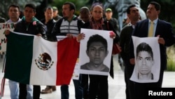 Para pemrotes memegang bendera Meksiko dan potret mahasiswa yang hilang di luar Kedubes Meksiko di Bogota, 7 November 2014 (Foto: dok).