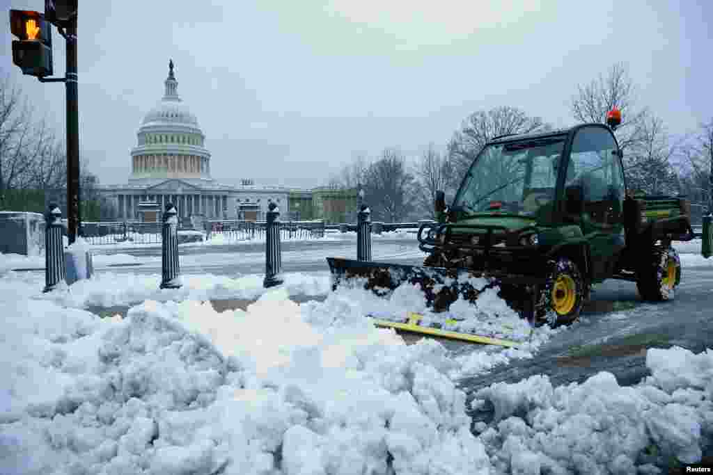 A worker clears snow from the sidewalks near the U.S. Capitol, March 17, 2014.