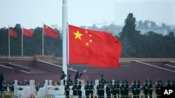 FILE - Chinese paramilitary policemen raise a flag in Tiananmen Square in Beijing, China. 