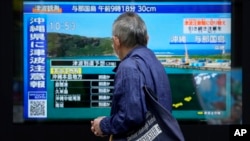 ARCHIVO - Una persona se encuentra junto a una acera mirando una televisión que muestra las últimas noticias sobre el tsunami en la región de Okinawa el 3 de abril de 2024 en Tokio.