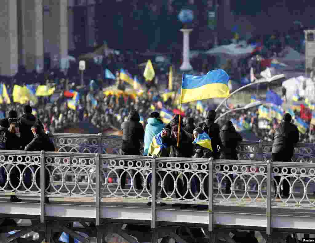 A man carrying a Ukrainian flag gestures as he stands on top of a bridge overlooking Independence Square, Kyiv, Dec. 4, 2013.