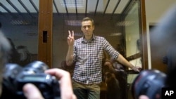 Russian opposition leader Alexey Navalny gestures as he posed for photographers standing in a glass enclosure at the Babuskinsky District Court in Moscow, Russia, Feb. 20, 2021. 