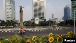 Seorang pengemudi taksi online melewati Bundaran Hotel Indonesia yang kosong saat pemerintah memberlakukan PPKM di Jawa dan Bali. (Foto: Reuters/Willy Kurniawan)
