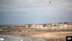 FILE, June 26, 2020 photo, people gather at a reopened beach on the first weekend after lockdown measures were lifted in Sale, Morocco, which will start gradually reopening its air and maritime borders after one of the world’s strictest lockdowns.