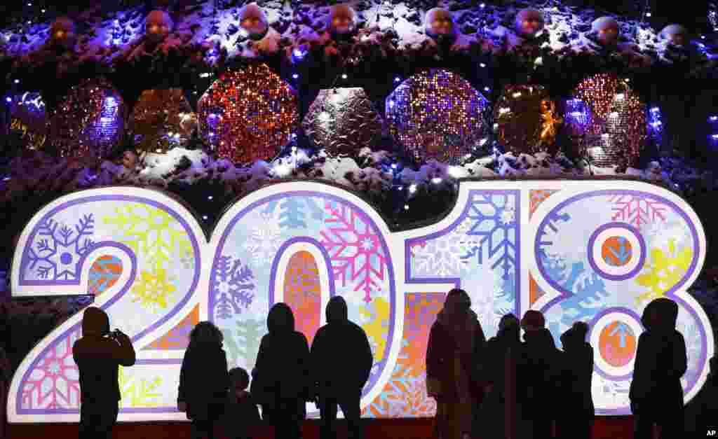 新年将至,白俄罗斯明斯克(Minsk)张灯结彩,人们站在广场上的2018年标志前(2017年12月22日)。
