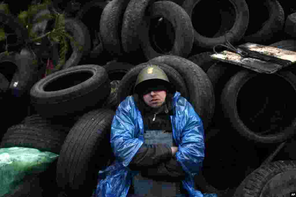 An anti-government protester sits and rest on a barricade at Independence Square in Kyiv, Feb. 21, 2014.