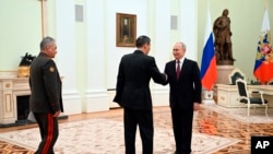 Russian President Vladimir Putin, right, greets China's Defense Minister Gen. Li Shangfu, center, as Russian Defense Minister Sergei Shoigu stands near at the Kremlin in Moscow, Russia, Sunday, April 16, 2023. (Pavel Bednyakov, Sputnik, Kremlin Pool Photo via AP)