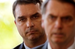 FILE - Flavio Bolsonaro, son of Jair Bolsonaro, is seen behind him at the transition government building in Brasilia, Nov. 27, 2018.