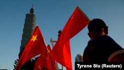 Pendukung Pro-China mengibarkan bendera nasional China di depan gedung landmark Taipei 101, di Taipei, Taiwan 22 Agustus 2016. (Foto: REUTERS/Tyrone Siu)