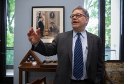 ARCHIVO - El senador Al Franken, demócrata por Minnesota, recuerda su comienzo en la política parado frente a una foto con su compañero de Minnesota Walter Mondale, quien fue senador y vicepresidente. Miércoles de junio. 15, 2016.