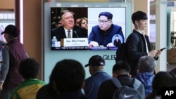 2018年4月18日，在韩国首尔火车站，人们观看电视新闻节目，屏幕上显示蓬佩奥和朝鲜领导人金正恩各自的肖像。