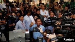 柬埔寨選民星期天投票,已經執政三十多年的首相洪森(中)在金邊郊區的電視台投票。