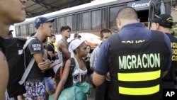FILE - Cuban migrants wait to board a bus to take them to a shelter, outside an immigration office at the border between Costa Rica and Nicaragua, in Penas Blancas, Costa Rica, Nov. 25, 2015.