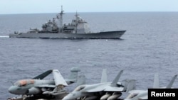FILE - U.S fighter jets on standby at the upper deck of a USS George Washington aircraft carrier while the USS Cowpens passes by, in the South China Sea, 170 nautical miles from Manila, September 2010.