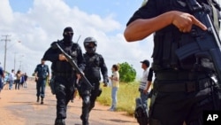 Heavily armed police officers walk outside the Agricultural Penitentiary of Monte Cristo, after dozens of inmates were killed, in Boa Vista, Roraima state, Brazil, Jan. 6, 2017.