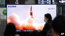 Arhiva - Ljudi gledaju TV program na kome se vidi fotografija severnokorejske nove vodeće rakete, tokom emisije vesti, na železničkoj stanici u Seulu, Južna Koreja, 26. marta 2021.