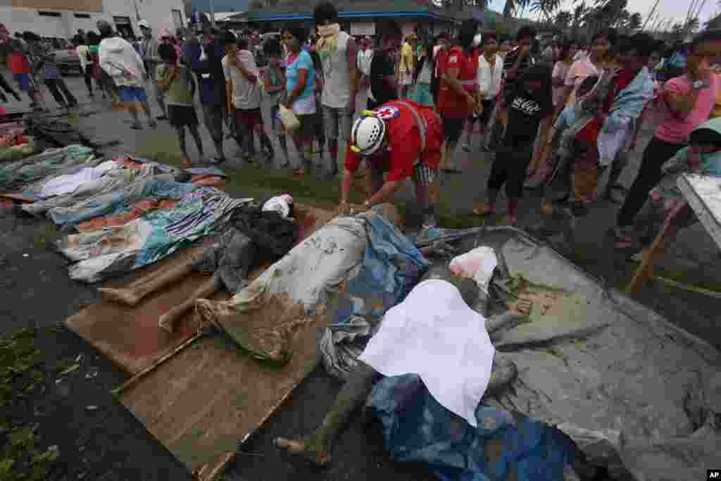 A rescuer covers bodies recovered from a flash flood in New Bataan, Compostela Valley province, southern Philippines, December 5, 2012.