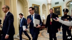 Treasury Secretary Steven Mnuchin, third from left, and White House Legislative Affairs Director Eric Ueland, left, walk to a meeting with Senate Minority Leader Sen. Chuck Schumer of N.Y. in his office on Capitol Hill, Monday, March 23, 2020, in…