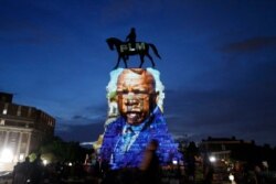 FILE - An image of the late Georgia Congressman and civil rights pioneer U.S. Rep. John Lewis is projected on to the pedestal of the statue of confederate Gen. Robert E. Lee on Monument Avenue, in Richmond, Va., July 22, 2020.