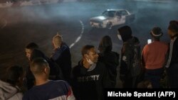 Des spectateurs acclament un conducteur qui fait virevolter sa voiture lors d'un événement de spinning à Alberton, en Afrique du Sud le 23 septembre 2021.