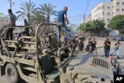 Warga Palestina mengendarai kendaraan militer Israel yang diambil dari pangkalan militer yang dikuasai militan Hamas di dekat pagar Jalur Gaza, di Kota Gaza, Sabtu, 7 Oktober 2023. (Foto: AP/Abed Abu Reash)
