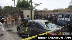 Polisi menjaga sebuah mobil yang diduga digunakan oleh orang-orang bersenjata di luar gedung Bursa Efek Pakistan di Karachi, 29 Juni 2020.