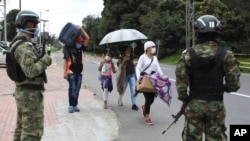 Bajo la vigilancia de soldados colombianos, migrantes venezolanos parten a pie hacia la frontera luego de un cierre ordenado por el gobierno en un esfuerzo por prevenir la propagación del nuevo coronavirus, en Bogotá, el lunes 6 de ab