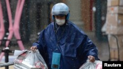An Ele.me deliveryman wearing a face mask delivers food amid snowfall, at a shopping area on Valentine's Day in Beijing, Feb. 14, 2020.