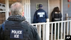 FILE - In this Feb. 9, 2017, photo provided U.S. Immigration and Customs Enforcement (ICE), ICE agents are seen at a home in Atlanta, Georgia, during a targeted enforcement operation aimed at immigration fugitives, re-entrants and at-large criminal aliens. 