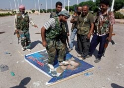 FILE - A Free Syrian Army fighter, center, steps on a poster depicting Syrian President Bashar al-Assad, at Tal Abyad, a Turkish-Syrian border crossing captured by the rebels, in eastern Syria, Sept. 22, 2012.