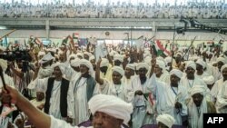 FILE - Supporters of Sudanese General Mohamed Hamdan Dagalo, also known as Himediti, deputy head of Sudan's ruling Transitional Military Council (TMC), raise up their sticks during a meeting with the General in the capital Khartoum, June 18, 2019. 